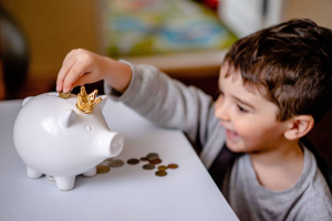 A child putting money in a piggy bank and smiling